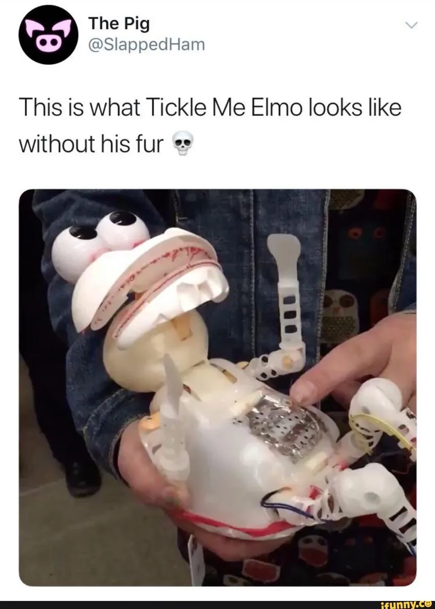A person holds a disassembled Tickle Me Elmo toy, revealing its white plastic internal mechanisms, wires, and exposed motor…