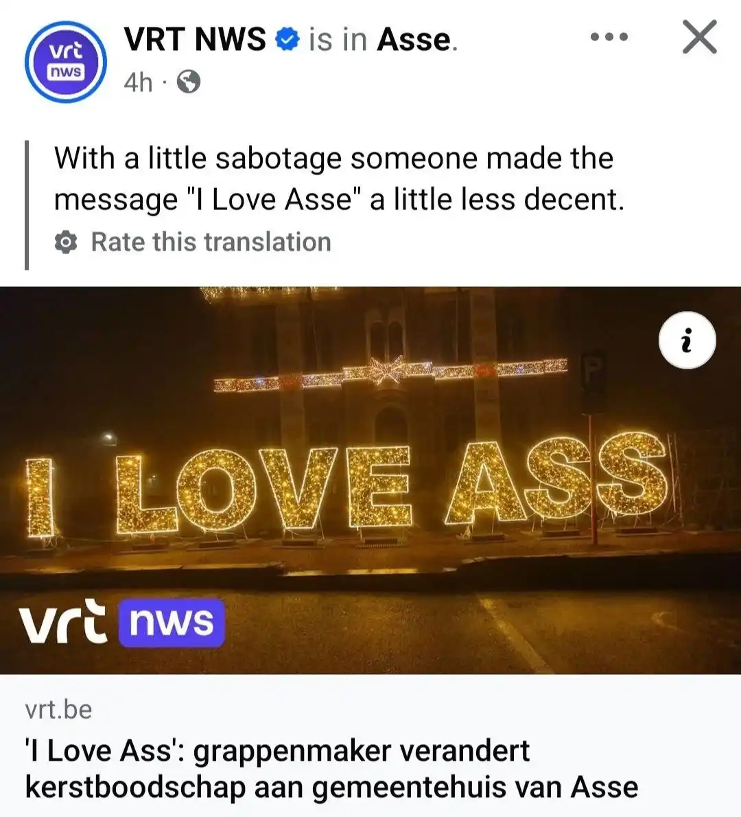 A screenshot of a VRT NWS social media post showing a nighttime photo of large, illuminated letters spelling "I LOVE ASS" in…