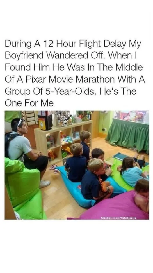 A man with a backpack sits on a green beanbag chair, watching a screen with a group of young children sitting on colorful…