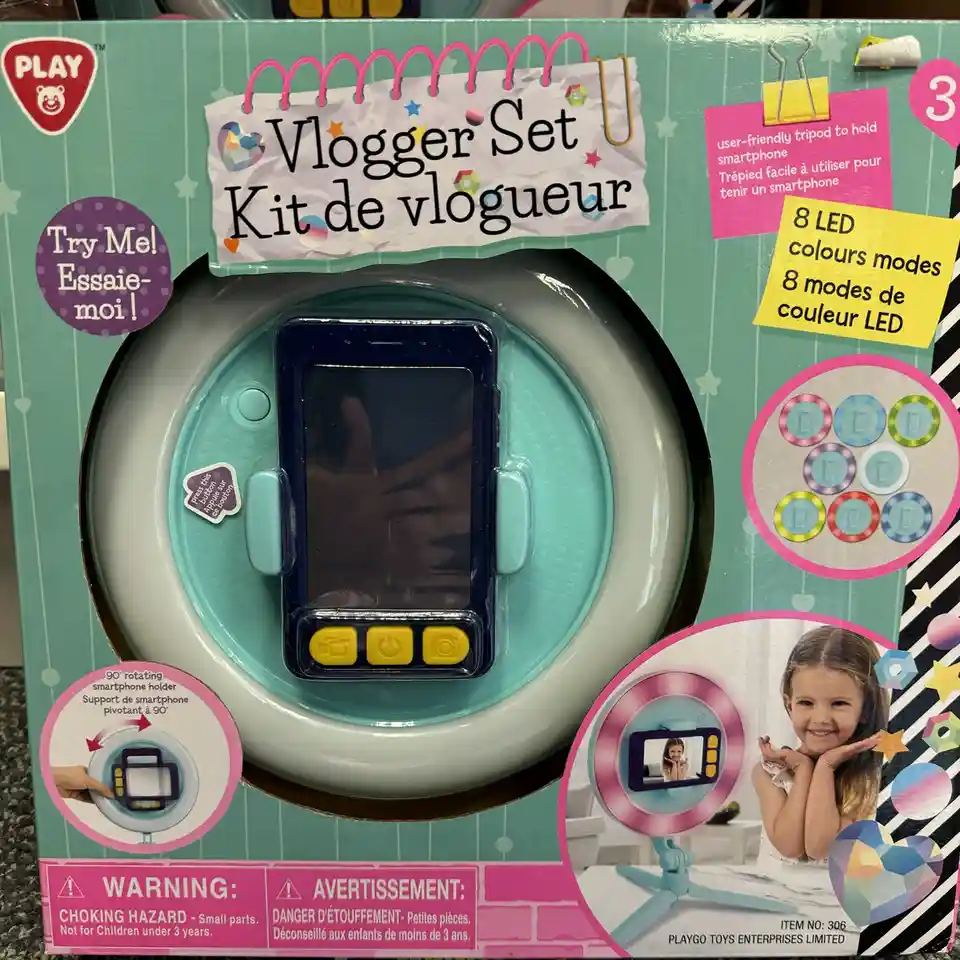 A toy product box for a 'Vlogger Set' by Play, featuring a child's smartphone holder with a ring light, buttons, and a…