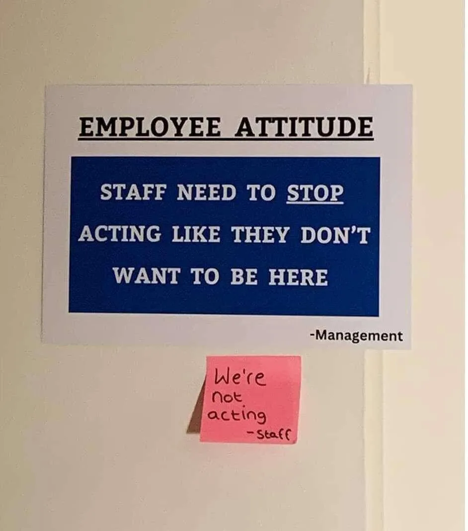 A printed sign on a wall reads 'EMPLOYEE ATTITUDE: STAFF NEED TO STOP ACTING LIKE THEY DON'T WANT TO BE HERE -Management'…
