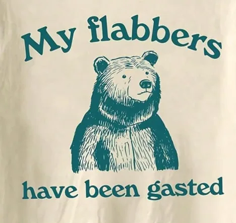 A beige t-shirt features a teal ink illustration of a bear with a slightly smug expression. Above the bear, the text 'My…
