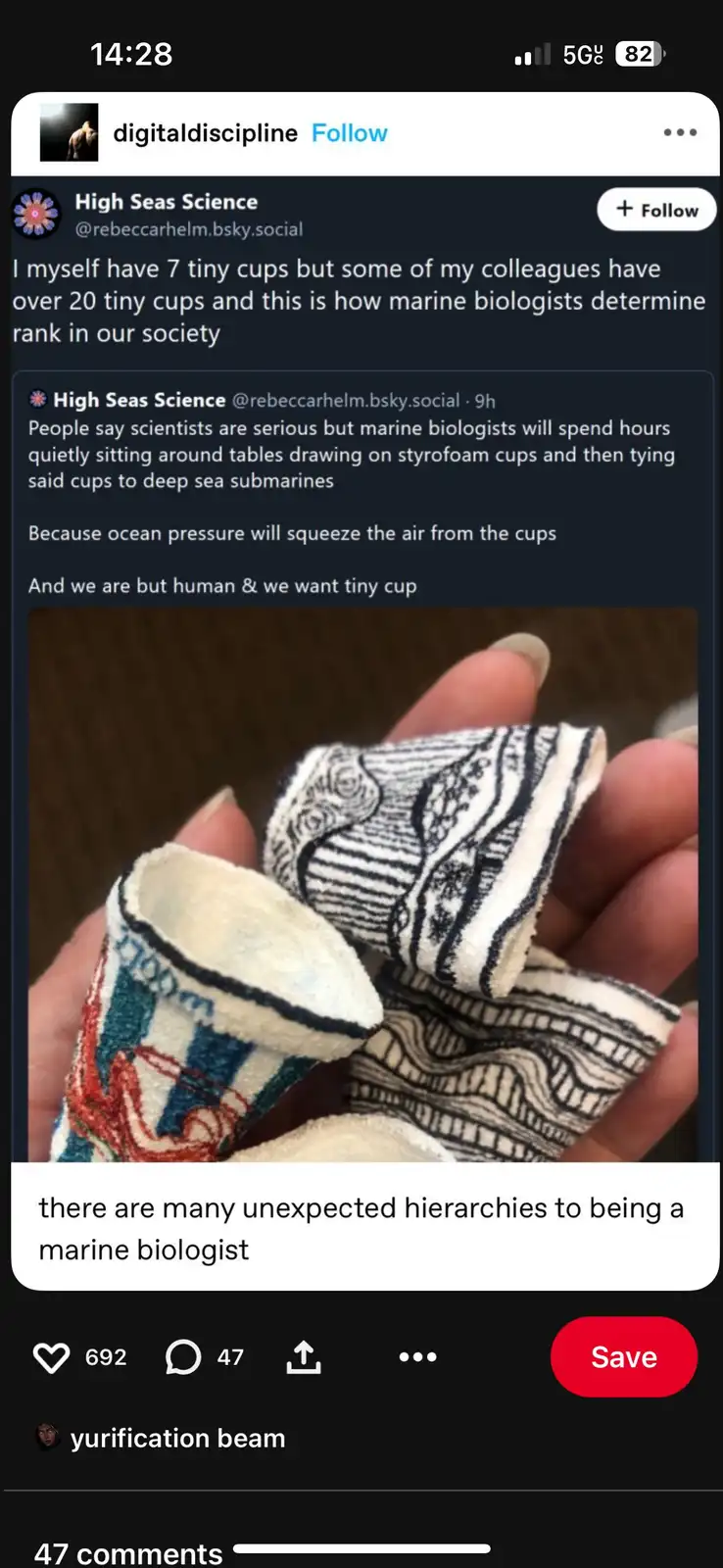 A close-up photo shows a hand holding two tiny, handmade-looking cups made of fabric with intricate black and white patterns…