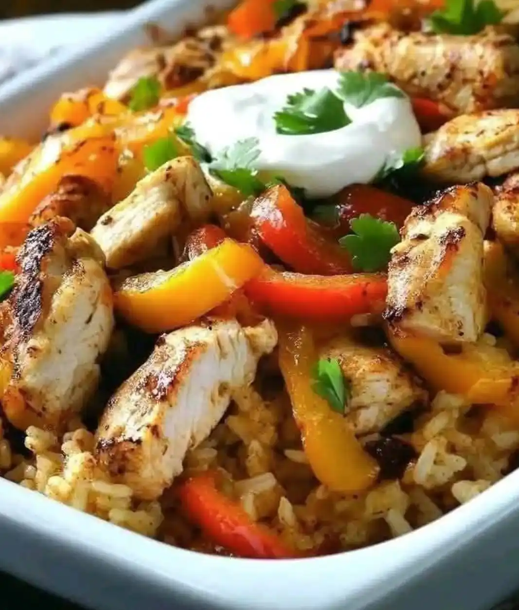A close-up photo of a colorful, appetizing dish featuring grilled chicken pieces, red and yellow bell peppers, rice, and a…
