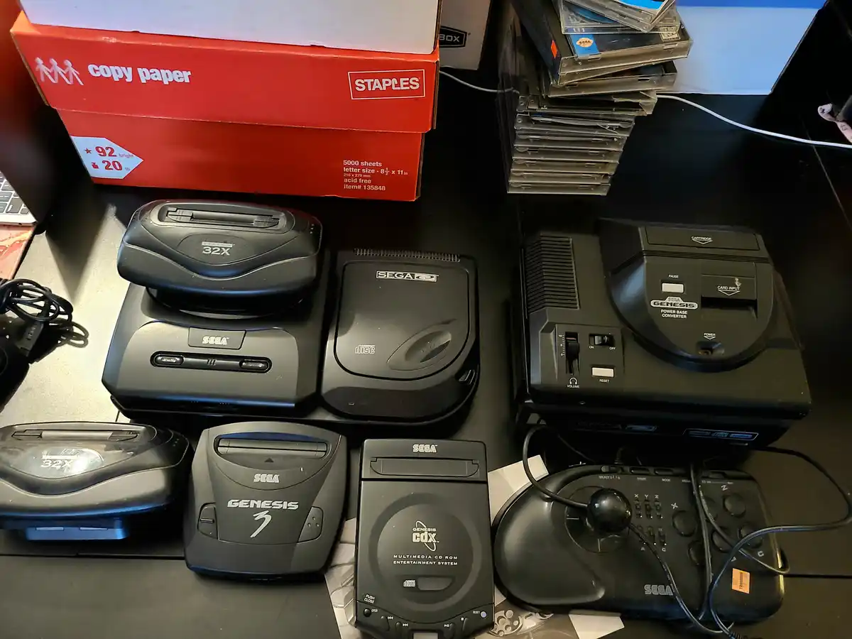 A collection of Sega Genesis gaming hardware, including multiple 32X add-ons, a Genesis 3 console, a Genesis CDX multimedia…