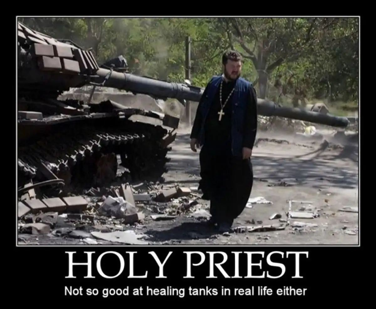 A man dressed as a priest with a cross necklace walks past a destroyed tank in a war-torn area with debris and dust. The…