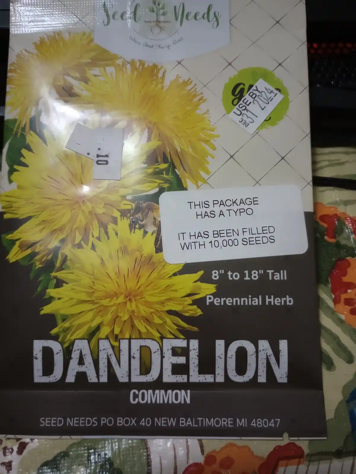 A seed packet for common dandelion features a white sticker that humorously claims the package has a typo and contains…