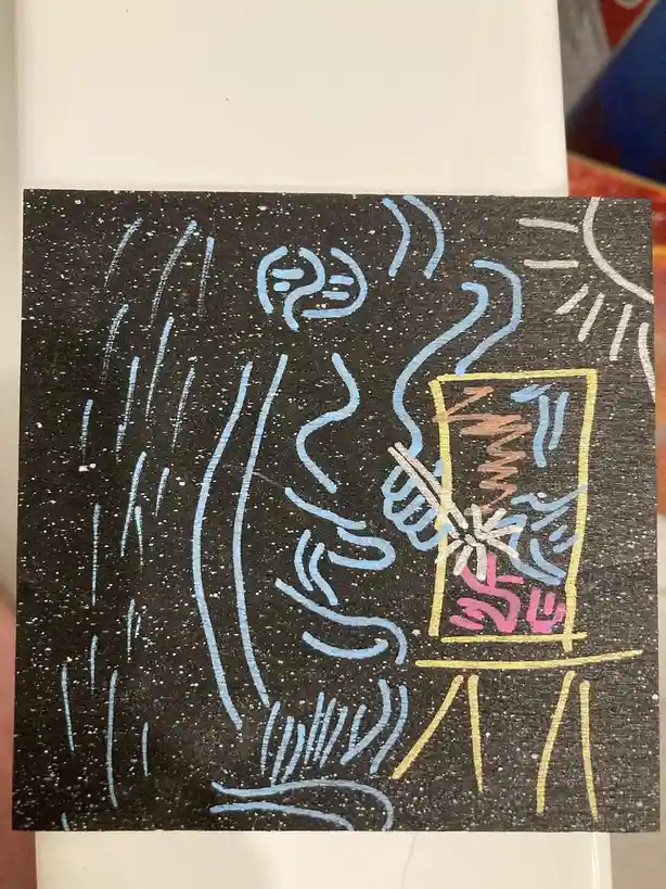 A child's crayon drawing on black speckled paper shows a person with blue lines for tears and a face, holding a…