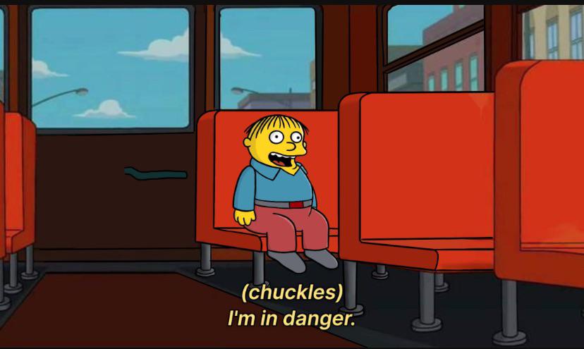 A cartoon boy with spiky hair sits alone on a red bus seat, looking terrified with wide eyes and an open mouth. The overlaid…