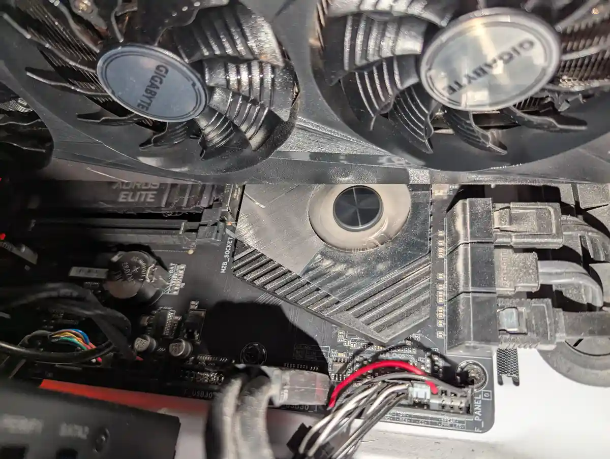 A close-up photo of a computer's internal components, showing a GIGABYTE-branded graphics card with two large cooling fans…