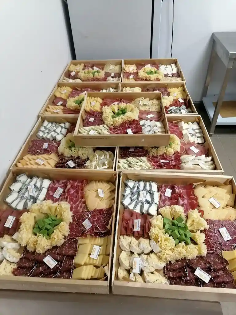 The image shows a large, organized display of numerous wooden trays filled with an assortment of sliced meats and cheeses…