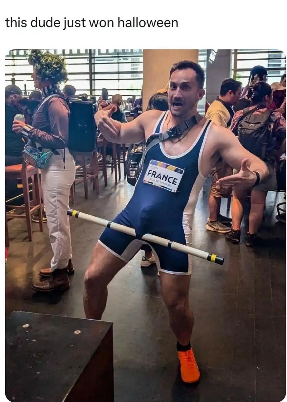 A man in a blue and white French wrestling singlet with a name tag reading 'FRANCE' and 'ANTHONY ABRIGATI' stands in a…
