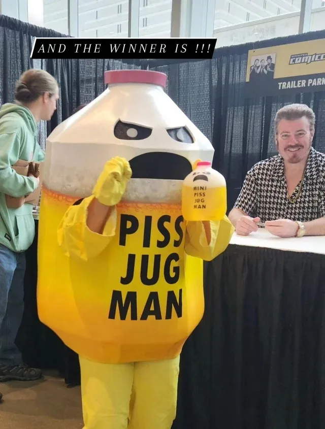 A person in a large, yellow and white costume resembling a jug with a face, labeled 'PISS JUG MAN', holds a smaller version…