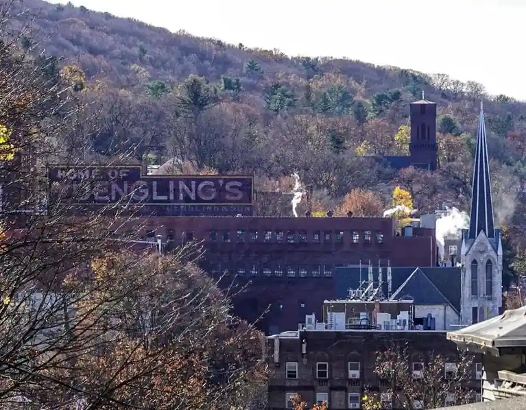 A wide shot of a brick industrial building with a faded mural reading 'HOME OF DENGLING'S' on its side, set against a…