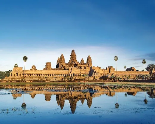 A serene, wide-angle photograph of Angkor Wat temple in Cambodia, its iconic stone towers and expansive structure reflected…