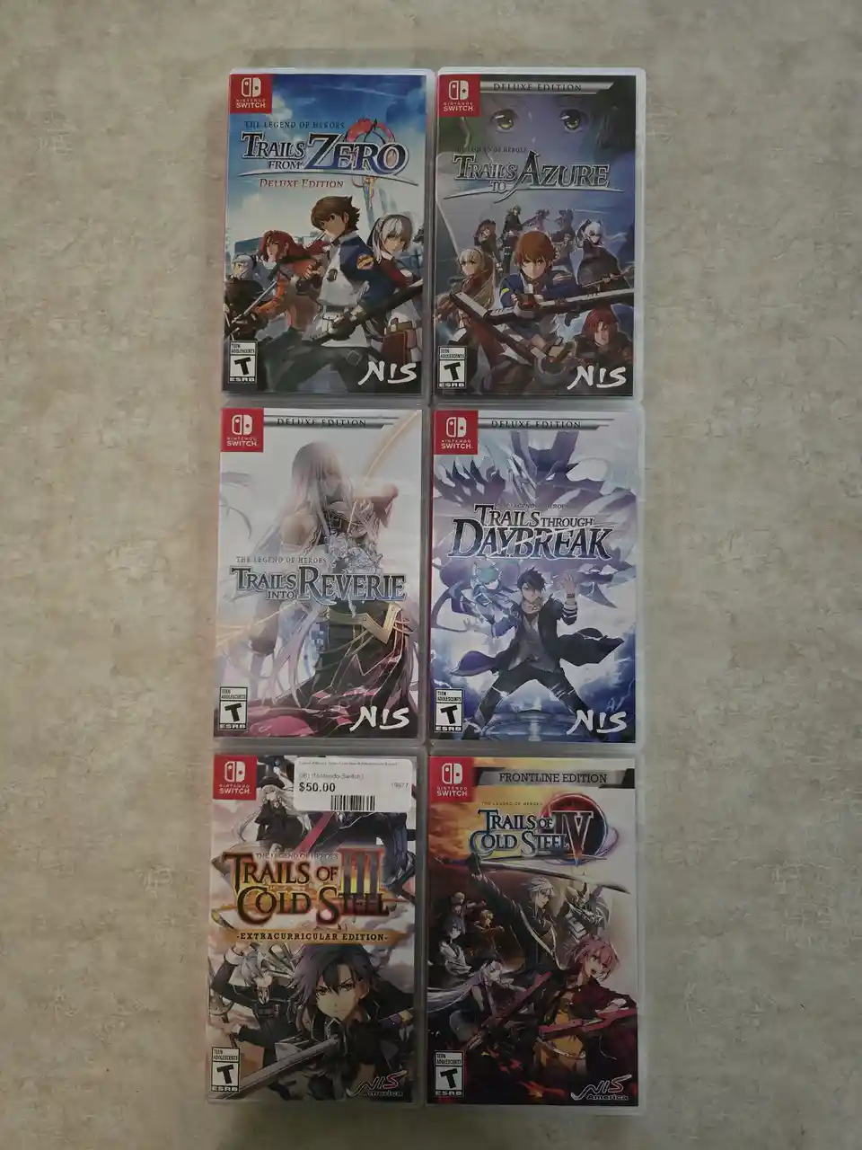 Six Nintendo Switch game cases for 'The Legend of Heroes' series are arranged in a grid on a beige surface. The games are…
