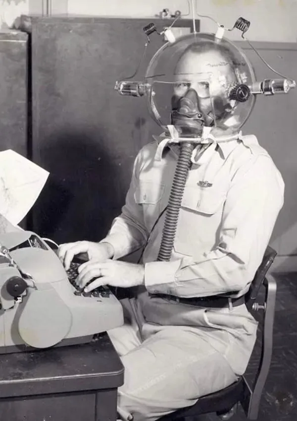 A man in a vintage military-style uniform sits at a desk typing on an old manual typewriter while wearing an elaborate…