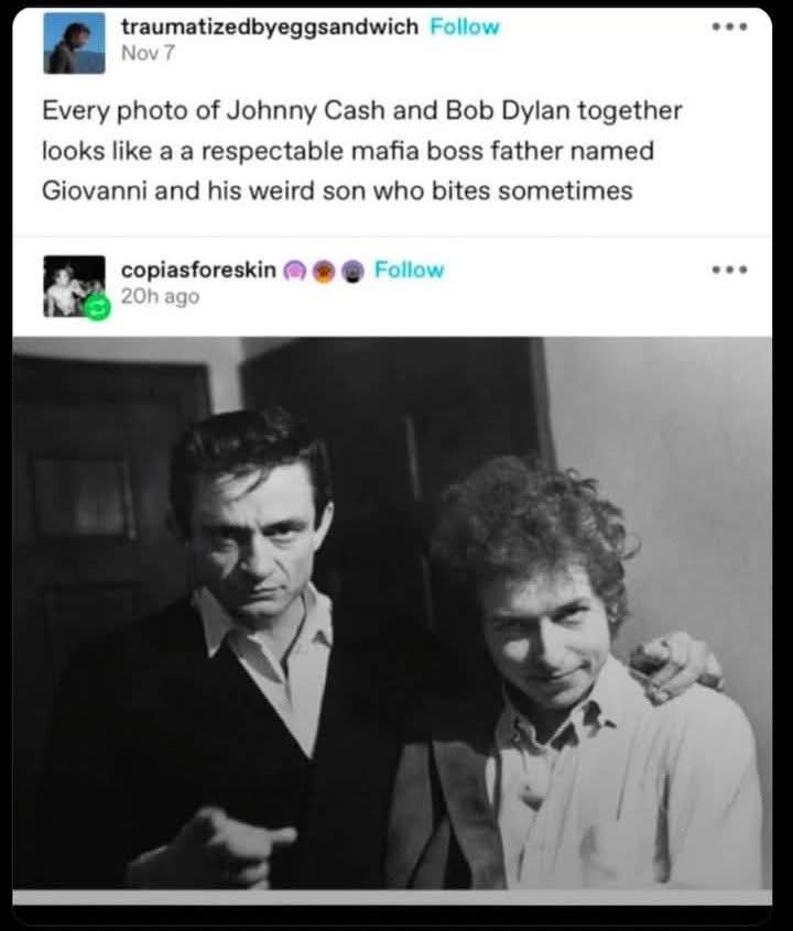A black-and-white photo shows Johnny Cash with a stern, serious expression, his arm around Bob Dylan, who is smiling…