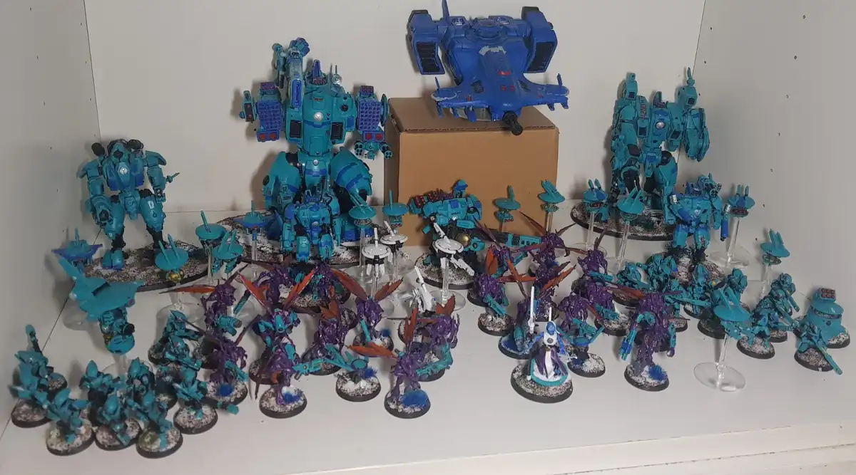 A large collection of painted miniature sci-fi models, mostly in teal and blue, displayed on a white shelf. The collection…