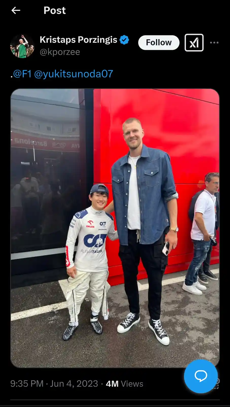 A tall basketball player, Kristaps Porzingis, stands next to a much shorter Formula 1 driver, Yuki Tsunoda, both smiling for…
