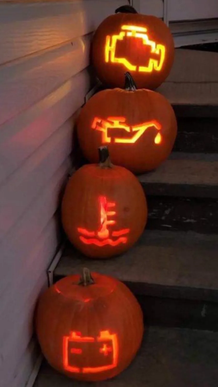 Four glowing jack-o'-lanterns are arranged on outdoor steps, each carved with a different illuminated automotive trouble…