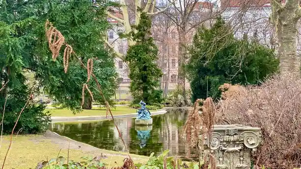A serene park scene with a pond, a blue statue in the center, and ornate stone elements, overlaid with the text 'i'm not…