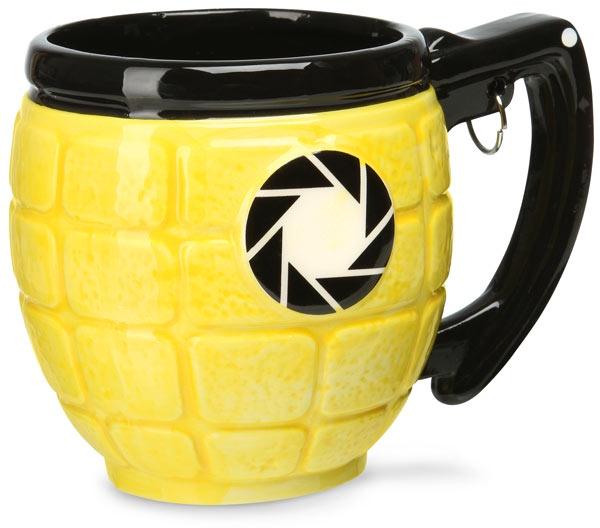 a yellow ceramic mug shaped like a hand grenade with a black handle and rim, featuring a black and white camera aperture…