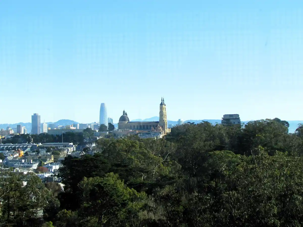 A scenic view of the San Francisco skyline, featuring the Transamerica Pyramid and a large church with a dome and bell…