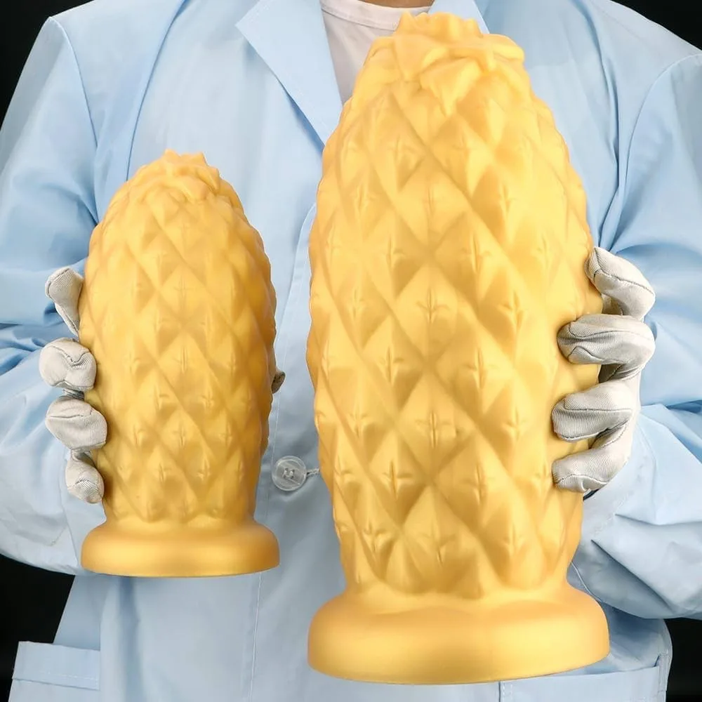 A person in a light blue lab coat and white gloves holds two oversized, yellow, pineapple-shaped objects, one in each hand…