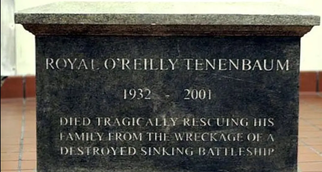 A dark stone tombstone with engraved text reads 'ROYAL O'REILLY TENENBAUM 1932 - 2001 DIED TRAGICALLY RESCUING HIS FAMILY…