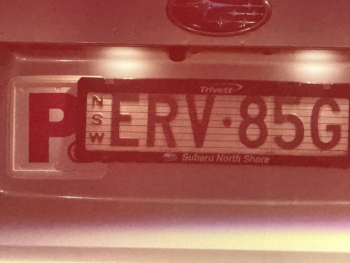 A close-up of an Australian NSW license plate with the registration 'PERV·85G' on a Subaru, where the 'P' is red and the…