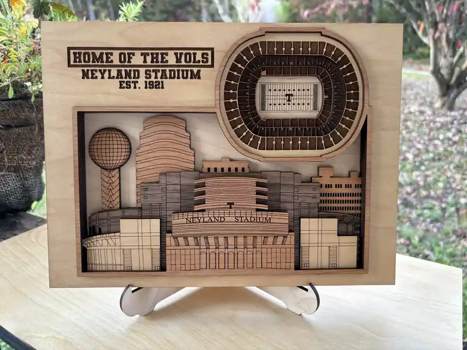 A wooden 3D laser-cut art piece displays Neyland Stadium, labeled 'HOME OF THE VOLS NEYLAND STADIUM EST. 1921', with a…