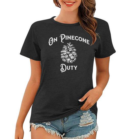 A woman wearing a black t-shirt with white text and a pinecone graphic that reads 'On Pinecone Duty' above and below the…