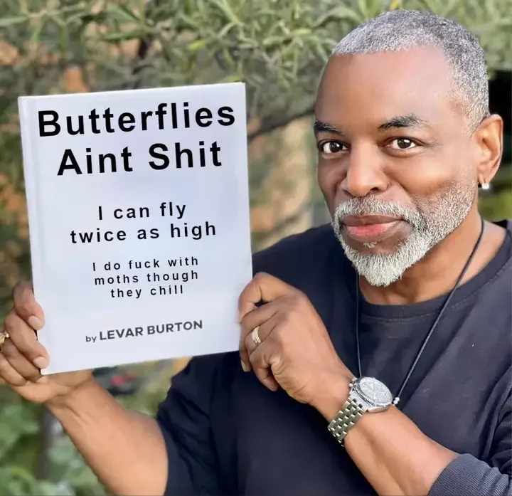 A man with gray hair and a beard holds up a white book cover that reads 'Butterflies Aint Shit', followed by 'I can fly…