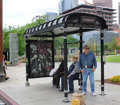 A photo of a bus shelter with a sign reading 'LOS ANGELES CITY HALL' above the roof, but the back wall is covered with a…