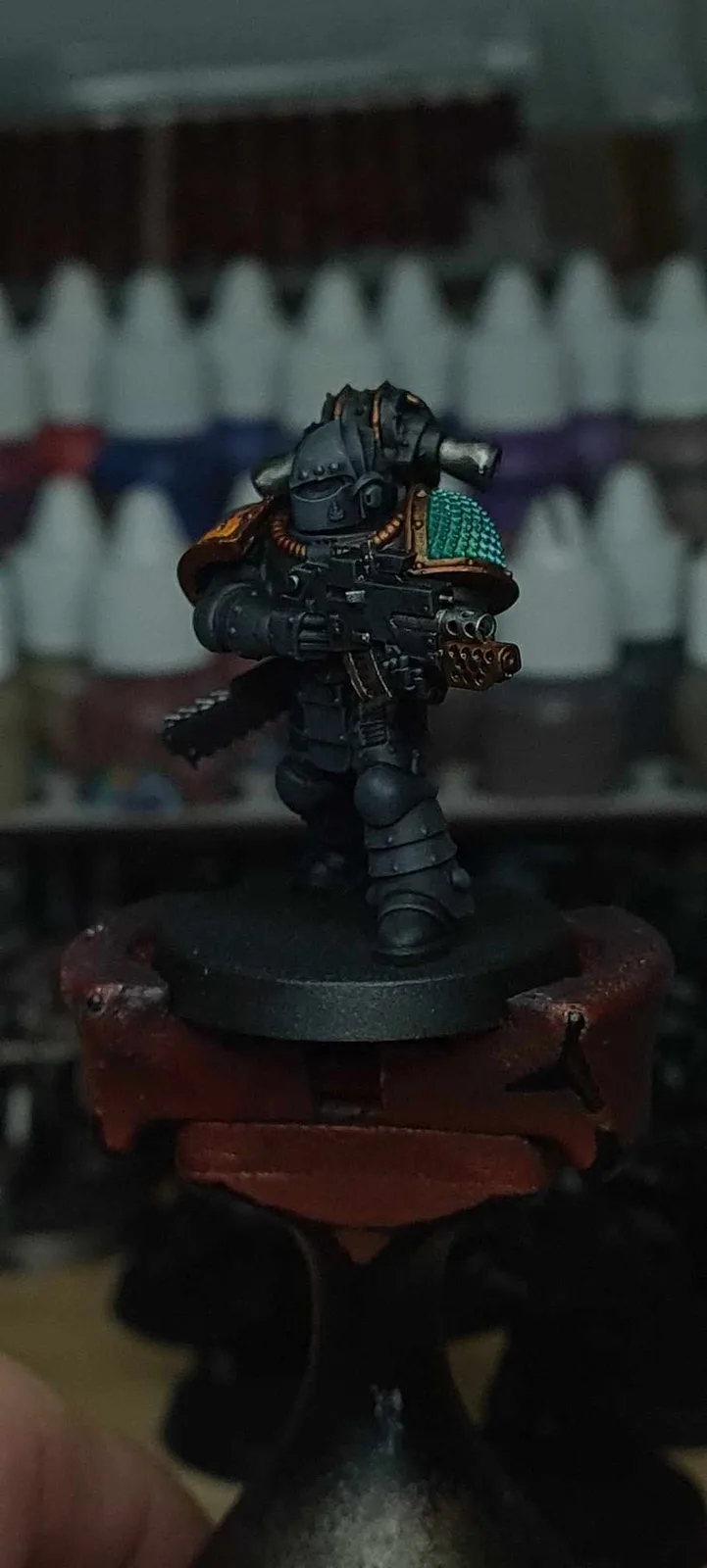 A heavily armored, custom-painted miniature warrior figurine stands on a black circular base, which is mounted on a red…