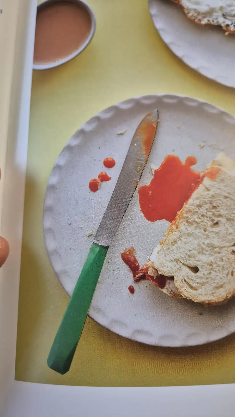 A close-up photo shows a plate with a slice of bread smeared with red sauce, a knife with sauce on its blade and handle, and…