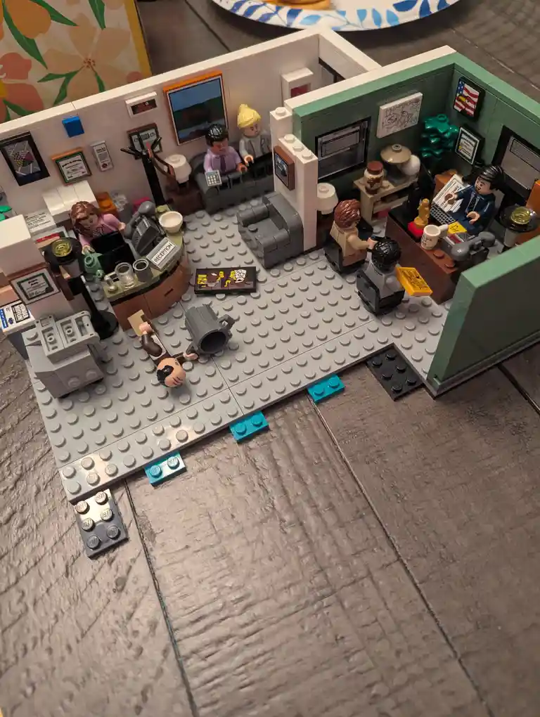 A detailed LEGO diorama of the Dunder Mifflin Scranton office from The Office, featuring minifigures in their respective…