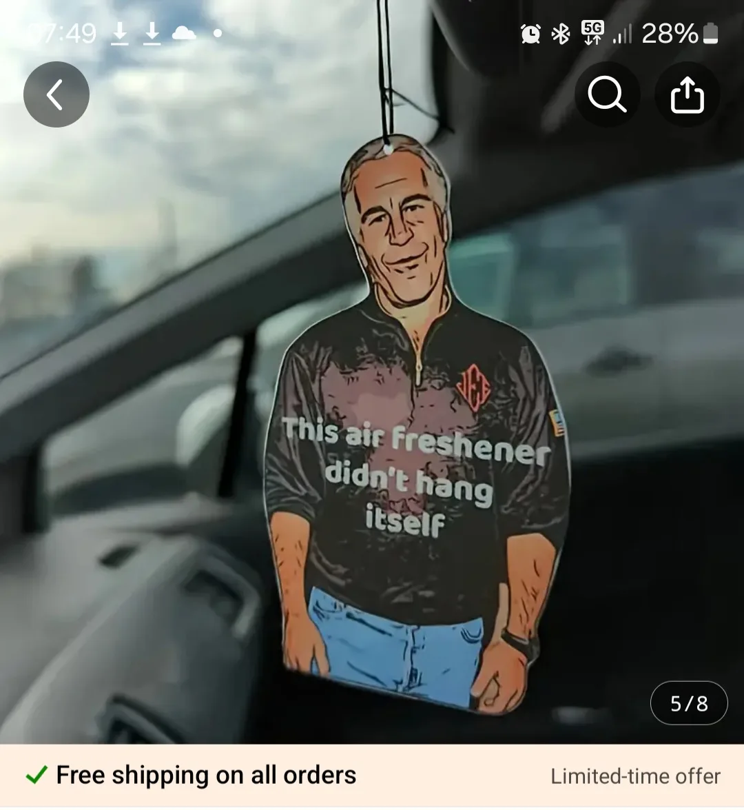 An air freshener shaped like a man in a black zip-up shirt and blue jeans hangs from a car's rearview mirror. The figure has…