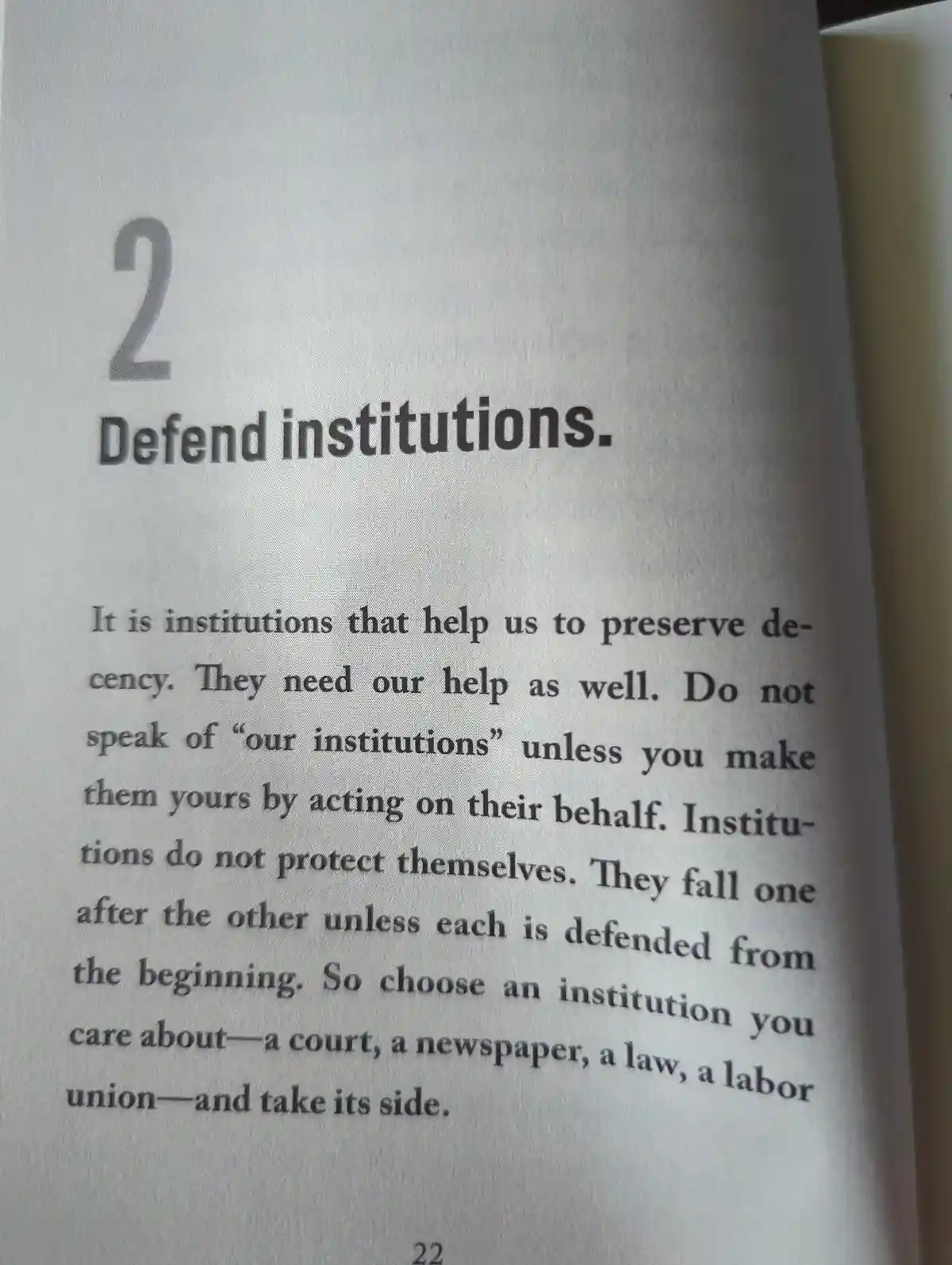 A close-up photo of a book page with the heading '2 Defend institutions.' The text below argues that institutions preserve…