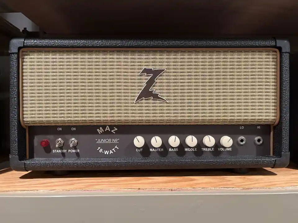 A close-up photo of a black and tan Marshall Junior NR 18-watt guitar amplifier head, featuring a woven grille cloth with a…