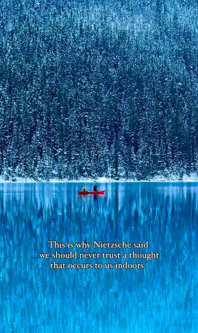A serene winter scene shows two people in a small red canoe on a calm, blue lake, with a dense forest of snow-covered…
