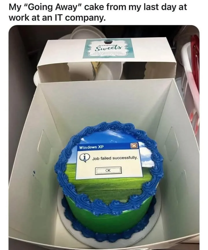 A round cake in a white box, decorated with blue frosting and a green field design, features a Windows XP error message…