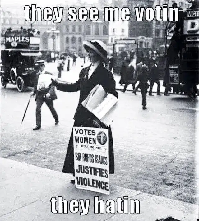 A black-and-white historical photo shows a woman in early 20th-century attire holding a protest sign that reads 'VOTES…