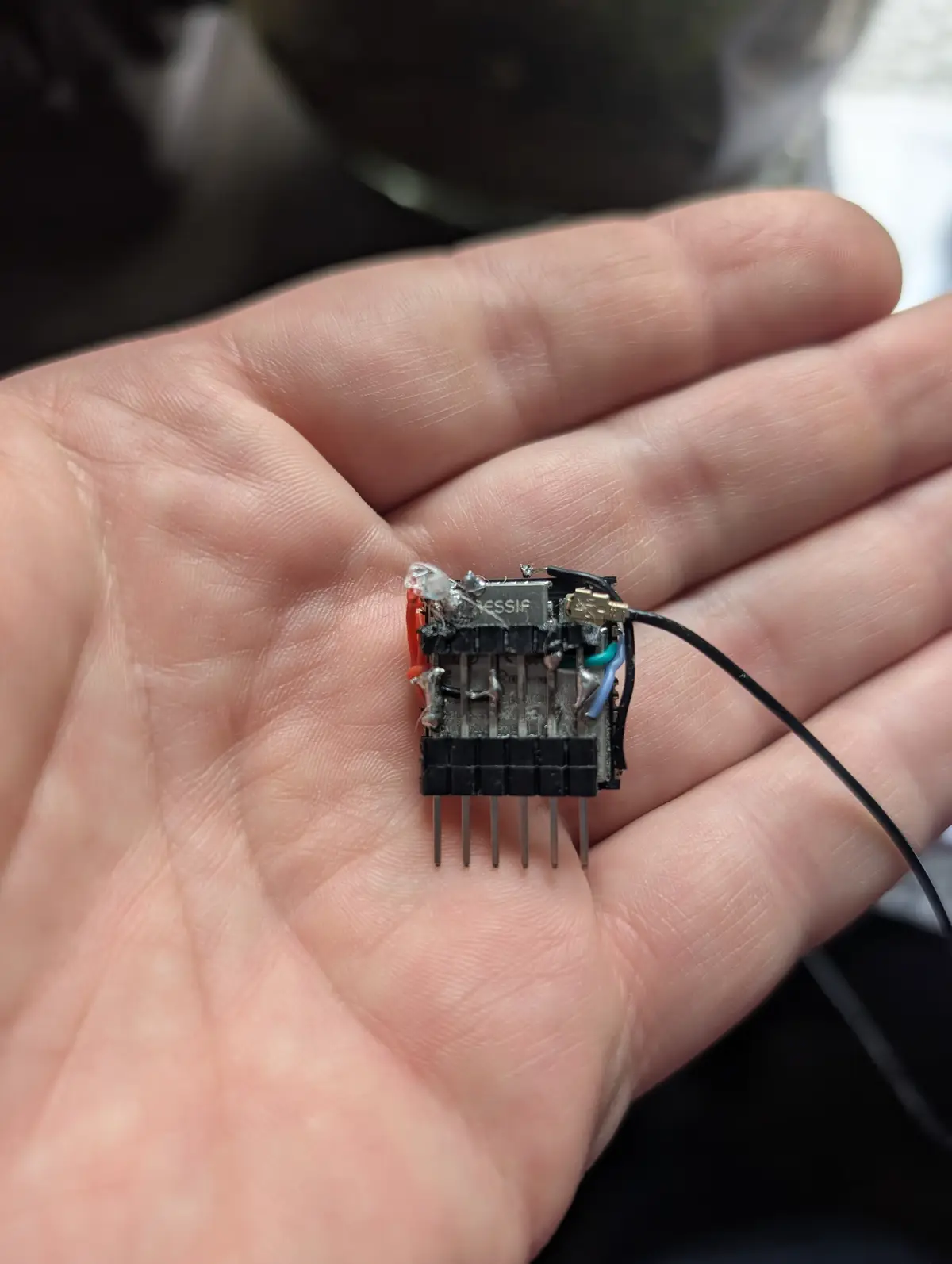 A close-up photo shows a person's open palm holding a small, visibly damaged electronic circuit board with melted components…