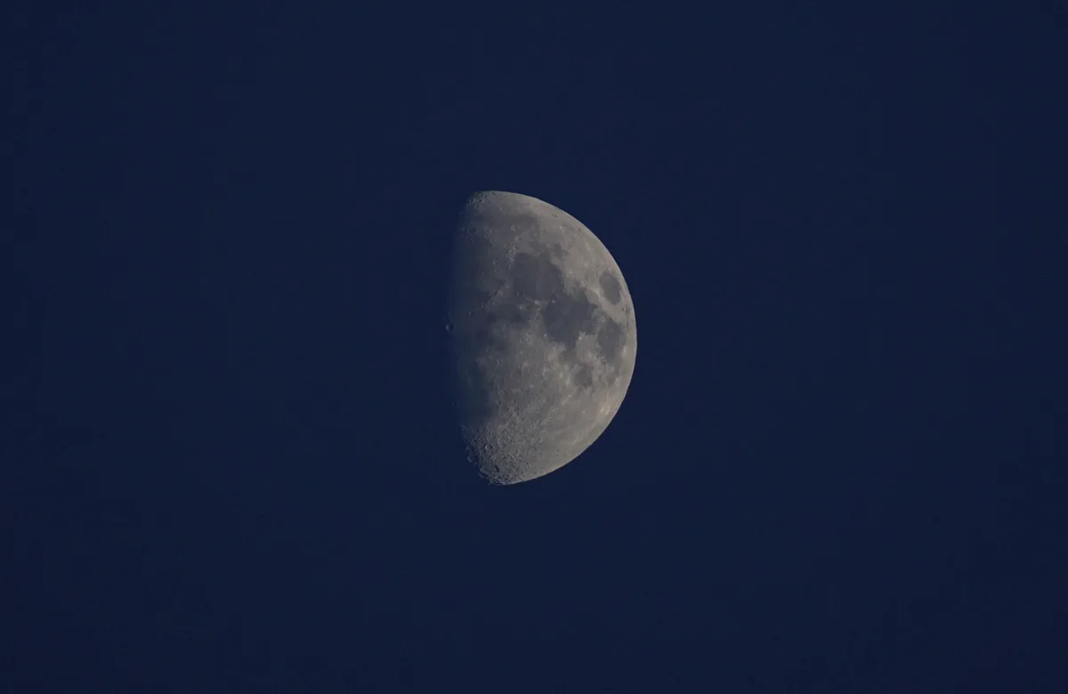 A photograph of a half-illuminated moon against a dark blue sky, with the text 'i'm not crying, you're crying' overlaid in…
