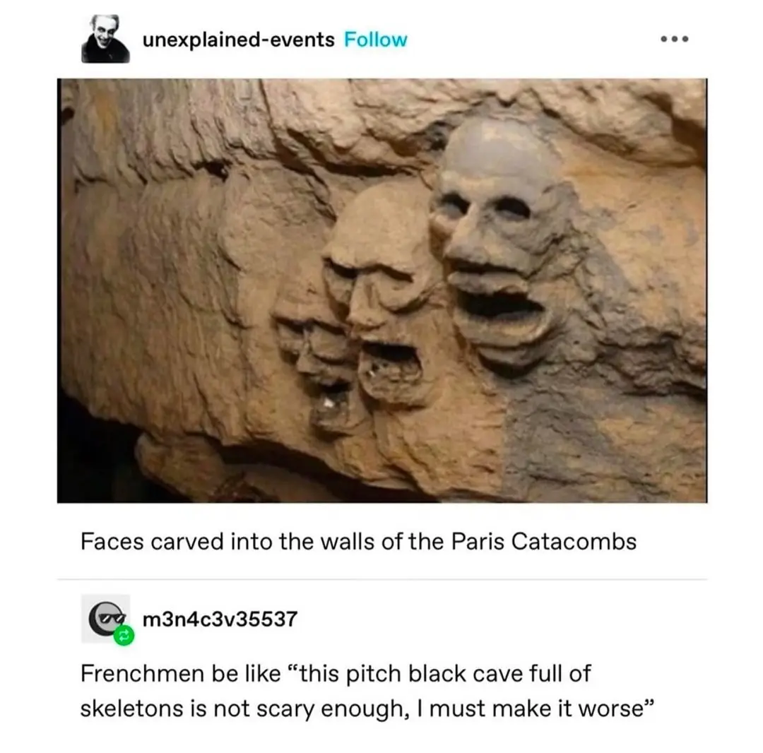 The image shows three grotesque, carved stone faces embedded in a rough, beige rock wall, resembling ancient or macabre…