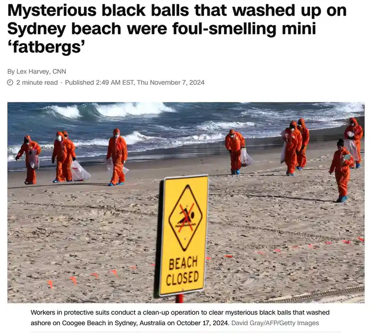 Workers in orange hazmat suits are cleaning up a beach with a 'BEACH CLOSED' sign in the foreground. The overlaid text…