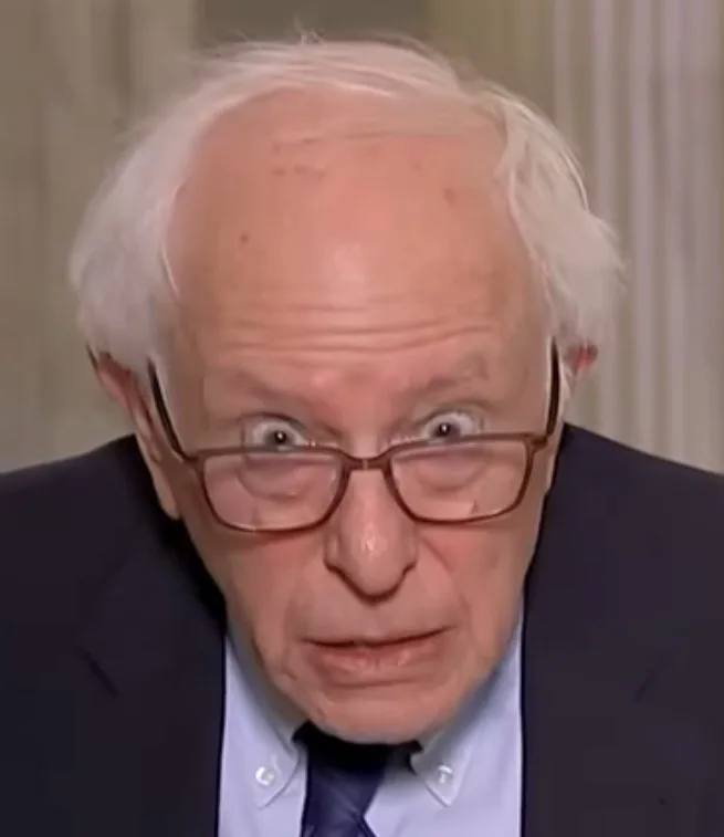 A close-up image of Bernie Sanders with wide, startled eyes and a shocked facial expression, wearing glasses, a dark suit…