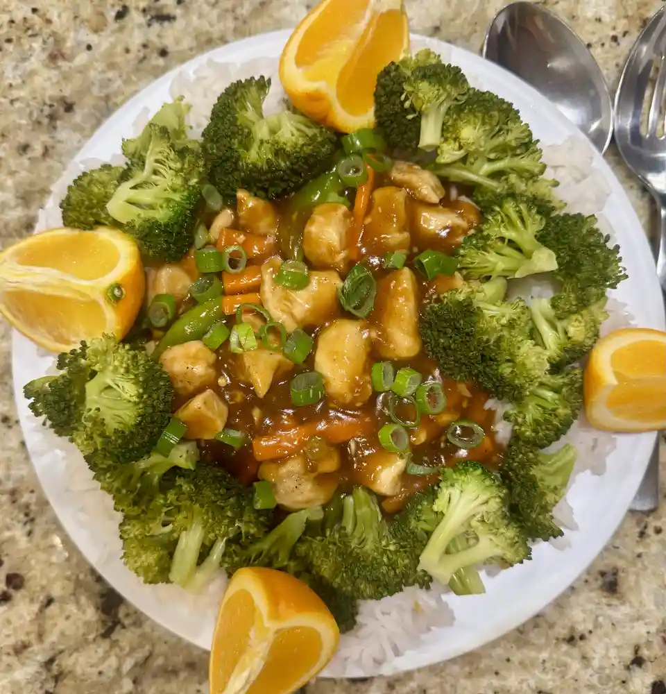 A plate of orange chicken with broccoli, rice, and orange wedges, overlaid with the text 'orange chicken'.